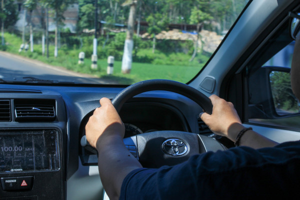 Hombre conduciendo en un auto con volante a la derecha en Indonesia.