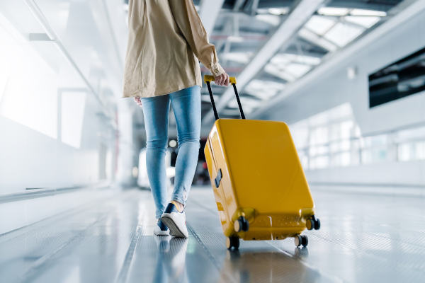 Mujer caminando en el aeropuerto con maleta amarilla.