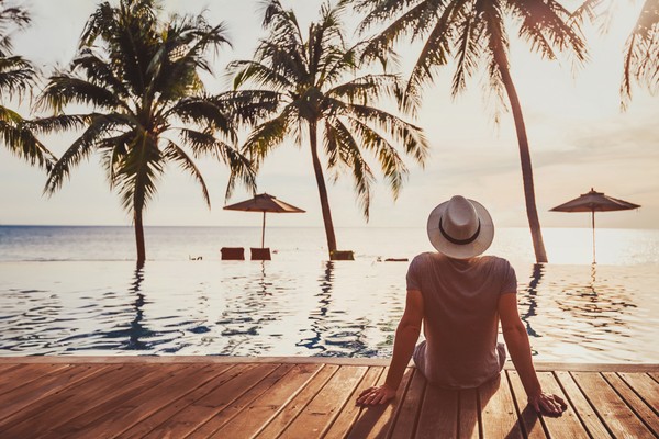 Vista trasera de una mujer arrastrando maleta amarilla por el aeropuerto.