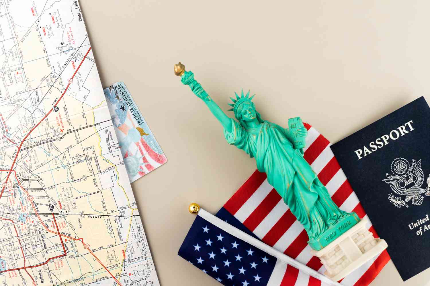 imagem de um mapa, uma miniatura da Estátua da Liberdade, um passaporte e uma bandeira dos EUA sob uma mesa