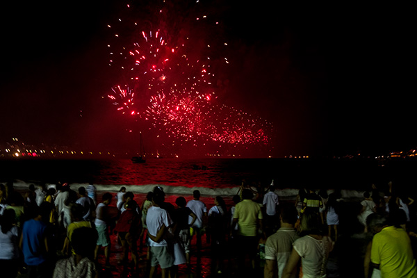 Personas mirando los fuegos artificiales en la playa durante el Réveillon