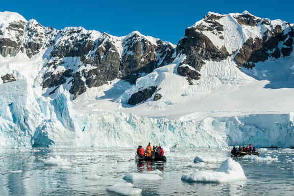 Turistas observando un glaciar sobre un zodiac en la Antártida, Argentina.