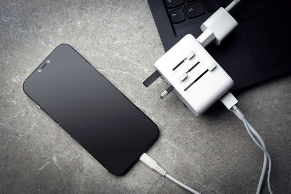 Celular y notebook conectados a un adaptador múltiple de corriente eléctrica.