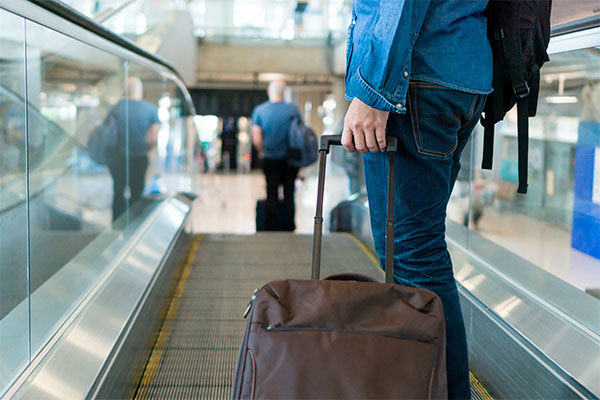 Un hombre en un aeropuerto con su equipaje en la mano.