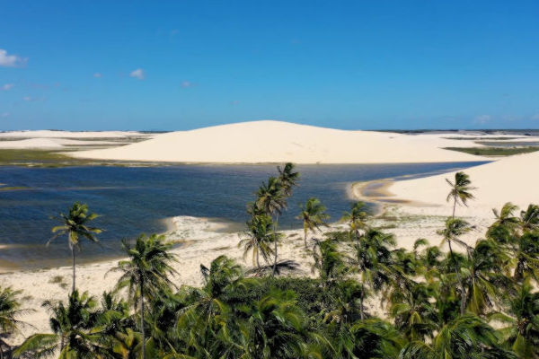Vista panorámica de los paisajes naturales de Jericoacoara, con dunas blancas, palmeras y lagunas de agua clara.
