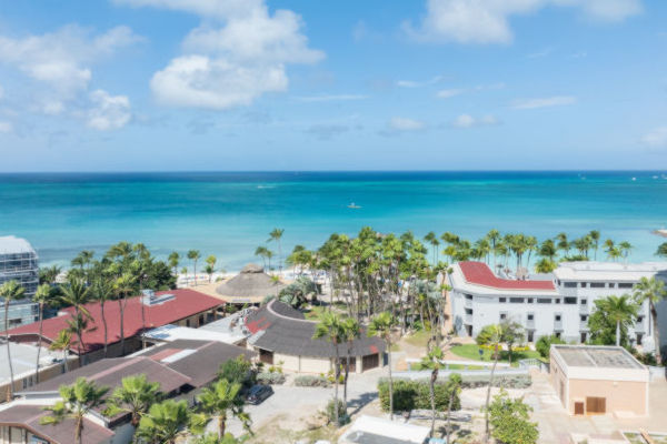 Vista aérea de la costa de Aruba con hoteles, palmeras y el mar Caribe de fondo.