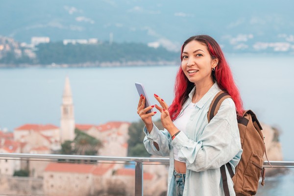 Turista con una mochila y un teléfono inteligente en Budva, Montenegro.