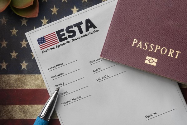 Formulario ESTA impreso junto con pasaporte y bandera de Estados Unidos.