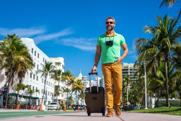 Hombre turista con maleta por las calles de Miami, Florida, Estados Unidos, en un día soleado.