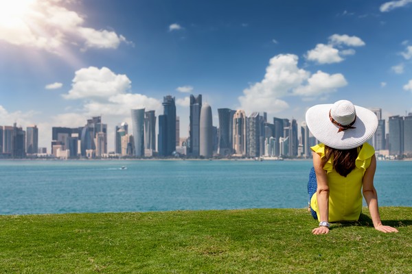 Mujer turista disfruta de la vista al horizonte de Doha, Qatar, desde un parque durante un día soleado con nubes.