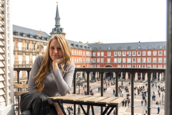 Joven turista sentada en un balcón con vista a la Plaza Mayor de Madrid.