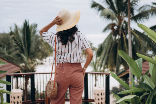Mujer de espaldas con sombrero de ala ancha observando el paisaje tropical desde una terraza en João Pessoa.