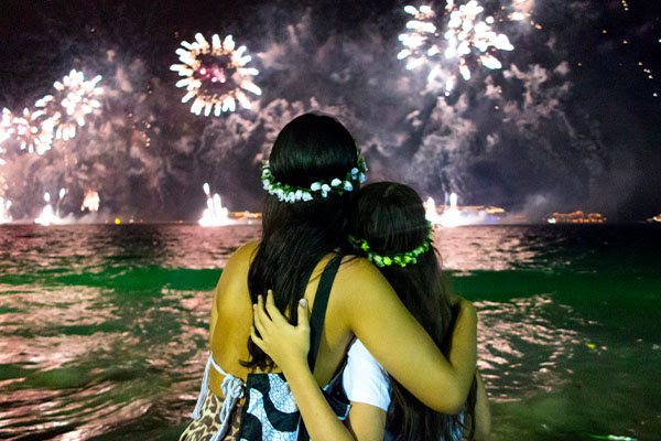 Madre e hija frente al mar viendo los fuegos artificiales del Año Nuevo en Río de Janeiro, Brasil