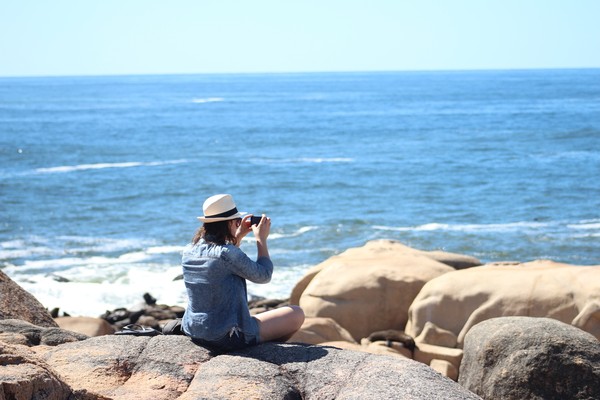 Mujer sentada sobre rocas en Punta del Diablo, Rocha, Uruguay