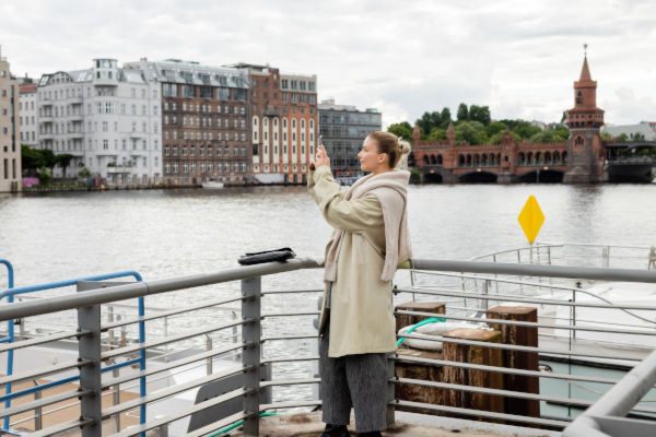 Turista fotografiando el paisaje urbano desde una baranda sobre el río Spree en Berlín.