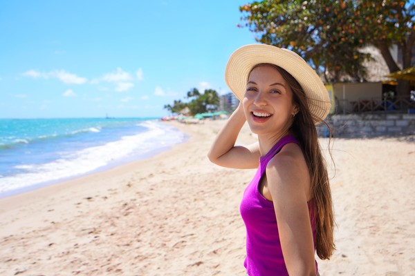 Mujer turista con sombrero sonriendo en una playa de Maceió, Brasil.