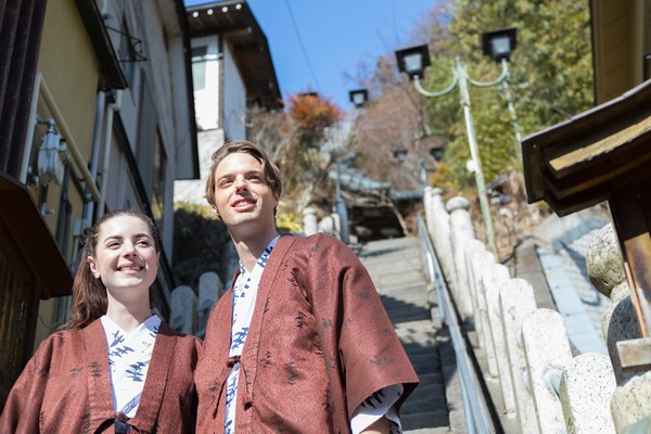 Pareja de turistas caucásicos con ropa tradicional japonesa en los alrededores de un balneario termal en Japón.