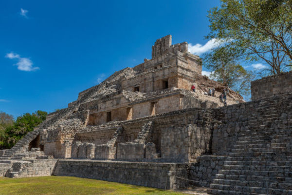 Templo maya de piedra en una zona arqueológica de México bajo un cielo despejado.