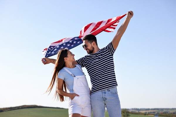 Feliz pareja ondea bandera de Estados Unidos al aire.