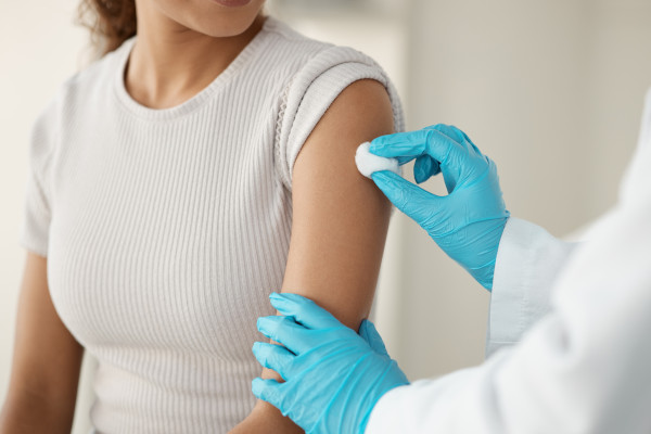 Personal de salud limpiando con algodón el brazo de una paciente que va a recibir una vacuna