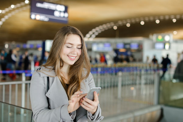mujer en el aeropuerto chequeando datos en su celular.