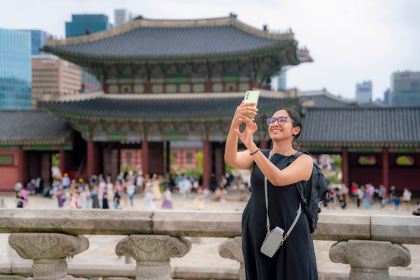 Mujer latina feliz joven con vestido negro tomándose se toma una selfie en las cercanías del Palacio de Gyeongbokgung, Corea del Sur.