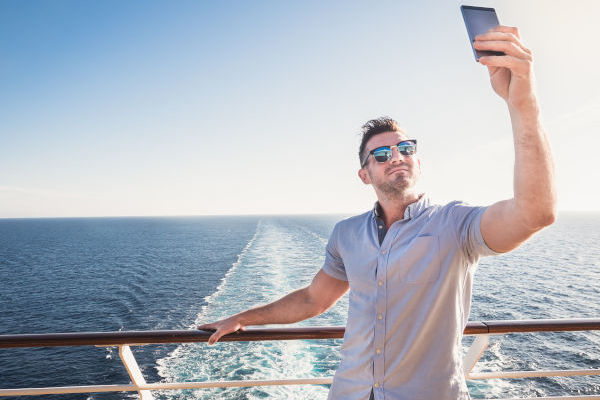 hombre sacándose una selfie en un crucero con el mar de fondo.