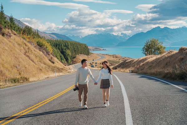 Pareja de la mano en una carretera junto al lago Pukaki en el mirador Peters Lookout, Nueva Zelanda.