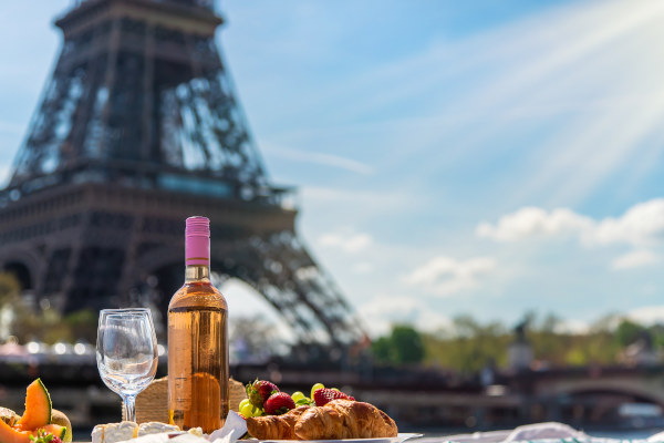 Picnic con croissants, frutas y vino con la Torre Eiffel de fondo en un día soleado en París, Francia.