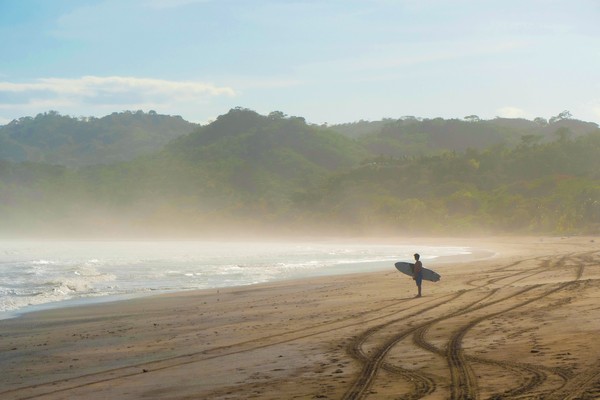 Silueta de surfista preparándose para entrar al mar temprano por la mañana en Playa Venao, Panamá.