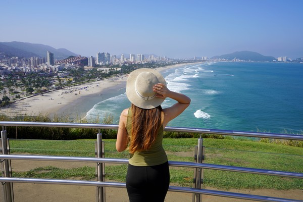 Mujer en bicicleta en una ruta patagónica con montañas a un lado y de fondo.