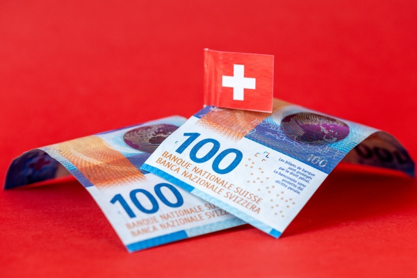 Billetes de francos suizos sobre una mesa junto a una bandera de Suiza.