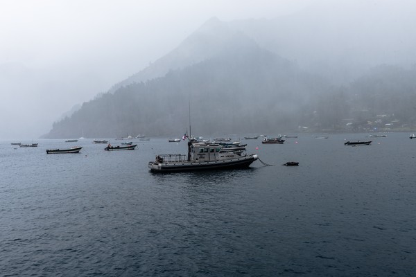 Barco anclado en el puerto de la isla Robinson Crusoe en un día con niebla espesa.