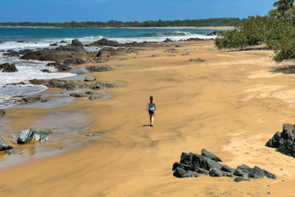 Mujer turista caminando por una impresionante playa tropical de Panamá y mirando hacia el océano.