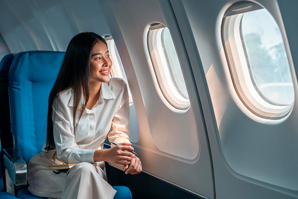 Mujer mirando por la ventanilla de un avión con una sonrisa