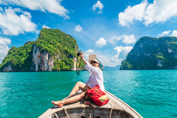 Viajera tomándose una foto en un bote tradicional tailandés en el área de Phuket, Tailandia, Sudeste Asiático.