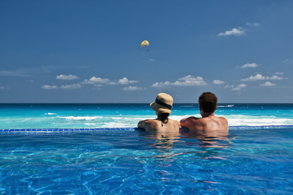 Pareja disfrutando de la vista al mar Caribe desde una piscina sin borde.