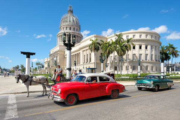 Escena típica habanera con autos antiguos frente al Capitolio, símbolo de la arquitectura y el encanto de Cuba.