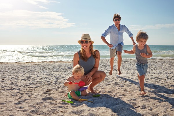 Familia tipo jugando en la arena, disfrutando de un día de playa.