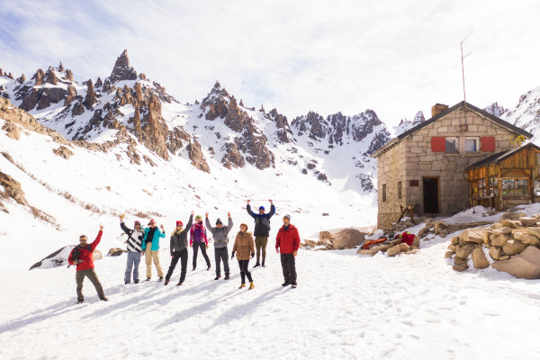 Grupo de senderistas en paisaje nevado de Bariloche celebrando entre montañas su arribo al Refugio Frey.