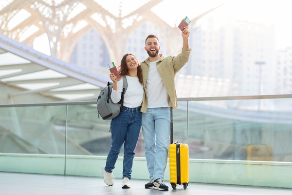 Pareja con pasaporte y billetes de avión en mano listos para subir a bordo en un aeropuerto.