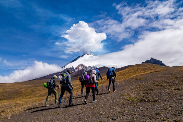 Grupo de senderistas en las cercanías del volcán Cotopaxi en erupción en un día soleado