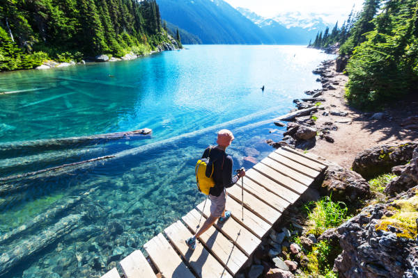 Senderista masculino cruzando un pequeño puente de madera en el lago Garibaldi, cerca de Whistler, Canadá.
