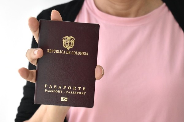 Persona que sostiene en su mano un pasaporte de la República de Colombia.