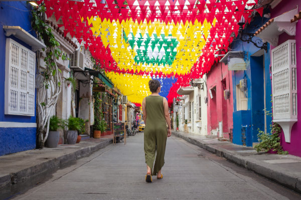 Turista caminando bajo coloridas banderas en las calles de Getsemaní, Cartagena de Indias, Colombia.