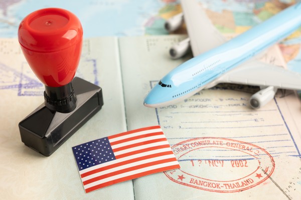 Bandera estadounidense con pasaporte sellado y avión en miniatura.