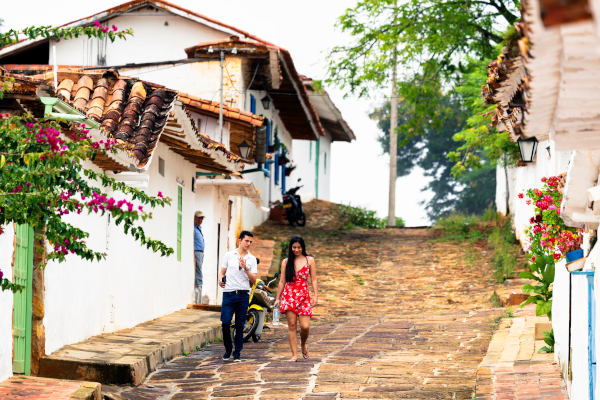 Pareja caminando cuesta abajo por las calles empedradas del pueblo colonial de Barichara, Colombia.