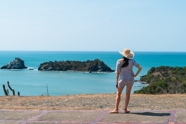 Mujer con vestido y sombrero con playa de Guayacán al fondo, Isla Margarita, Venezuela.