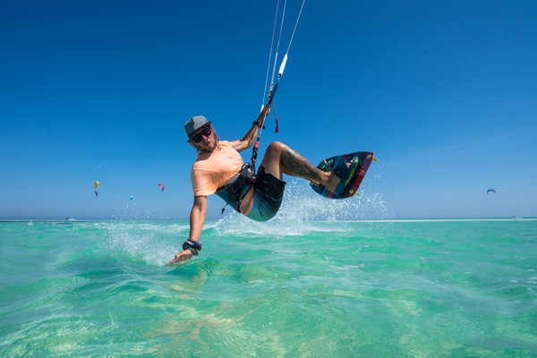 Hombre practicando kitesurf en un mar calmo con aguas cristalinas.