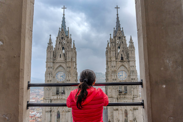 Turista observando la Basílica del Voto Nacional en el centro histórico de Quito en un día nublado